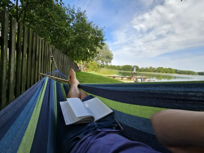 wypoczynek na hamaku z książką i widokiem na jezioro i niebo